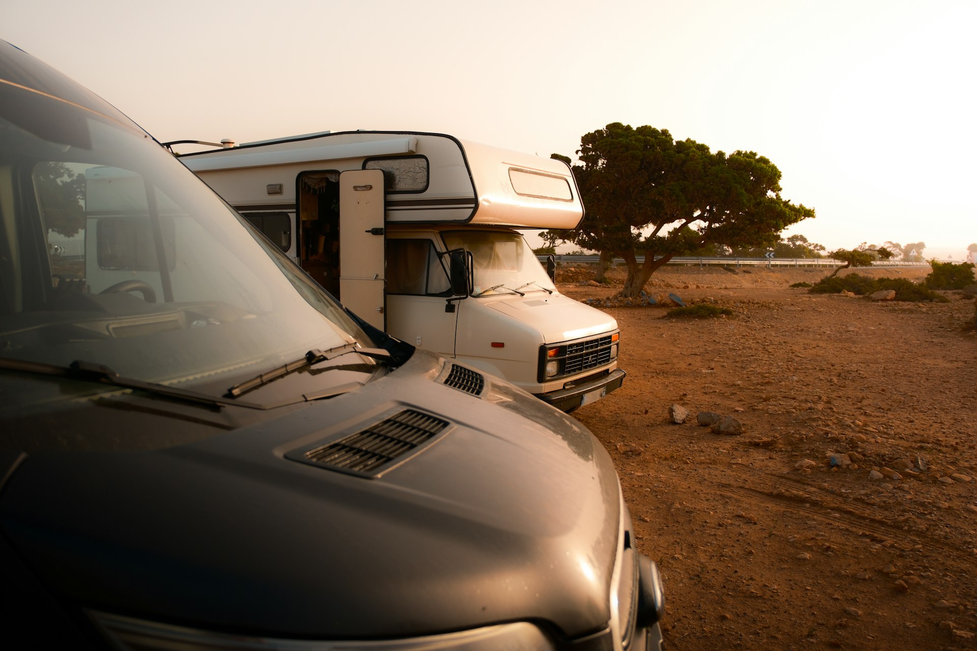 a couple of vehicles parked next to each other on a dirt field